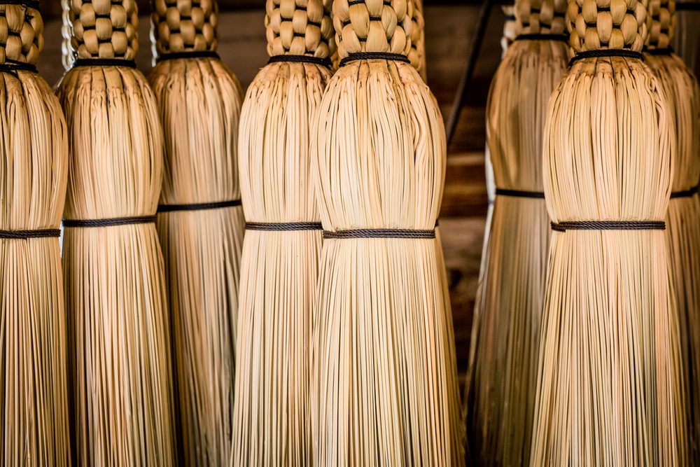 Handwoven corn brooms hanging to keep their shape